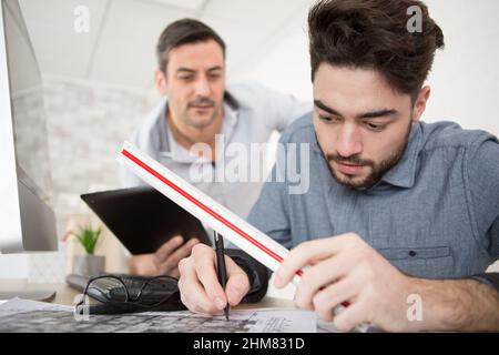 apprentice architect making blueprints using a scale ruler Stock Photo