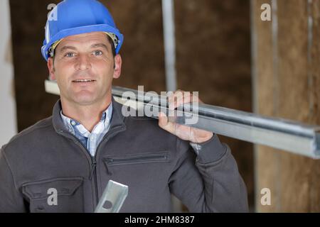 smiling construction worker carrying a metal bar Stock Photo