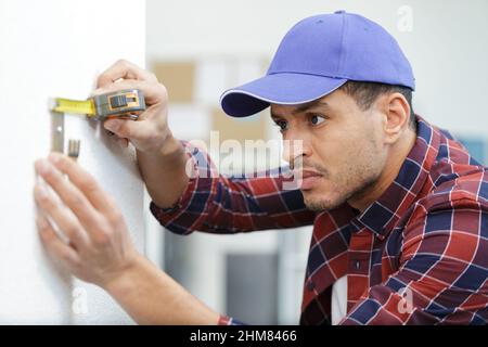 construction worker measuring bracket in a new house Stock Photo