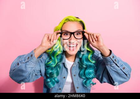 Photo of sweet impressed young vibrant woman wear jeans shirt arms spectacles smiling isolated pink color background. Stock Photo