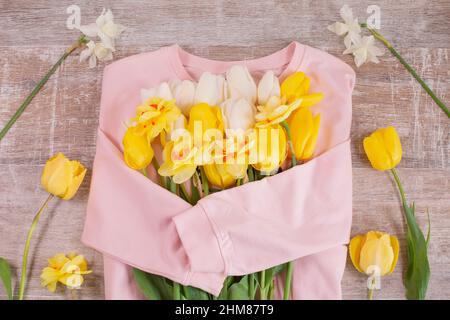Bouquet of color tulips and daffodils on pink sweater. Spring concept. Hello Spring. Top view layout. Stock Photo