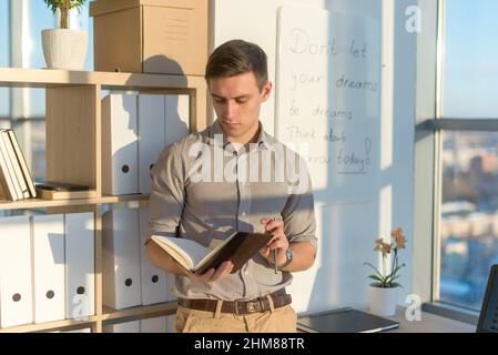 Man working in office, planning work tasks, writing down his schedule to planner at the workplace Stock Photo