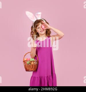 Content kid with basket covering eye with Easter egg Stock Photo