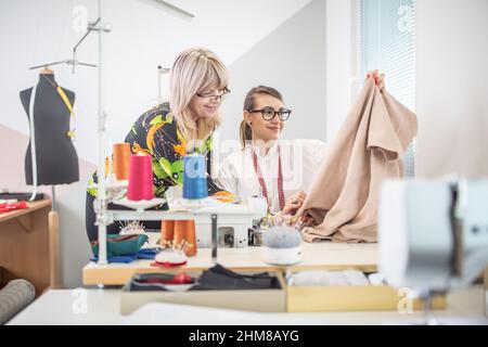 Positive working environment as two female tailors check the quality of their work in a small workshop. Stock Photo