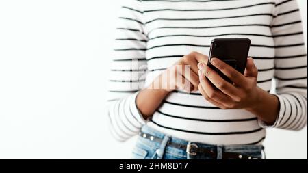 Wherever I go Ive got my loved ones with me. Cropped shot of a woman using a smartphone against a white studio background. Stock Photo