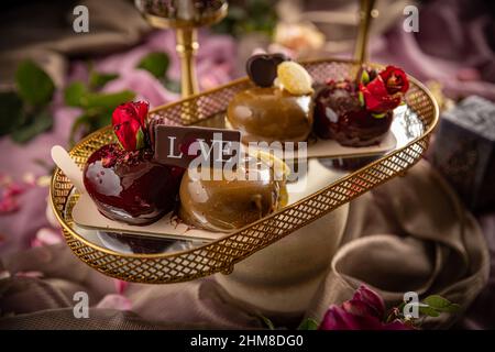 Still life of heart shaped mini cakes decorated with rose Stock Photo