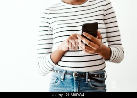 Smart tech keeps your social life alive. Cropped shot of a woman using a smartphone against a white studio background. Stock Photo
