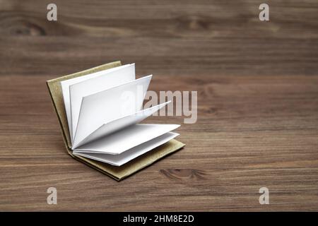 Accordion open miniature book with blank pages on a wooden table. Stock Photo