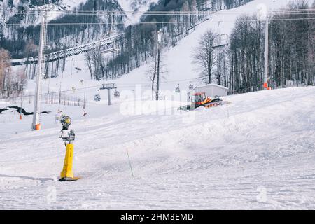 Sochi, Estosadok, Russia, 31 March 2021: Red modern snowcat ratrack with snowplow snow grooming machine preparing ski slope piste hillalpine skiing wi Stock Photo