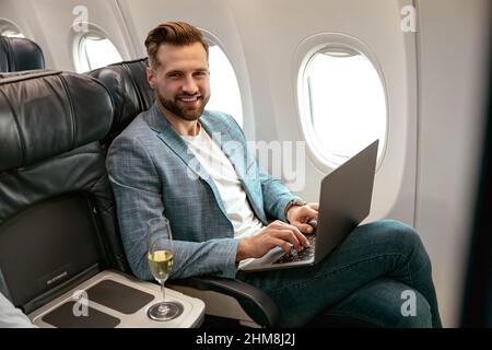 Cheerful bearded man using laptop in airplane Stock Photo