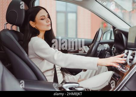 Woman turning on car air condition system on dashboard in car panel, Auto car air condition. Stock Photo