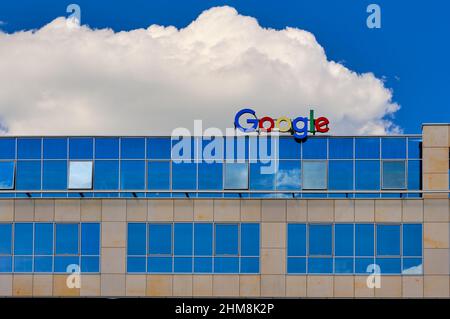 Wroclaw, Poland - Jun 6, 2021. Google sign or logo on top of the office building. Blue sky, daytime, big white cloud. World-scale corporations Stock Photo