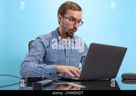 Portrait of man, IT programmer, web developer working on software isolated over blue background Stock Photo