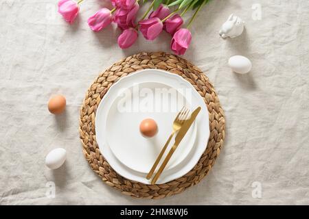 Spring Easter table setting with organic eggs, pink tulips on linen tablecloth. View from above. Stock Photo