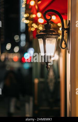 Vintage Lantern at Night. Old Fashioned Glowing Lantern. Lamppost on wall. Stock Photo