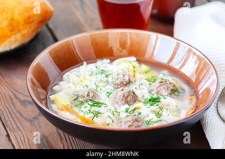 Homemade meatballs soup with noodles on a wooden background. Close up. Stock Photo
