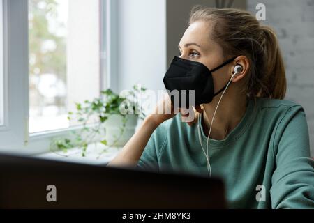 worried depressed woman wearing face mask in office at work and looking out of the window. mental health and burnout concept Stock Photo