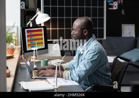 African architect with disability sitting at his workplace and typing on laptop, he working with online project at home Stock Photo