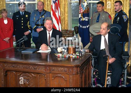 U.S. President Bill Clinton, joined by James Brady, right, Rep. Carolyn McCarthy, left, and members of law enforcement for the signing of a directive on child safety gun locks from the Oval Office of the White House, March 5, 1997 in Washington, D.C. Stock Photo