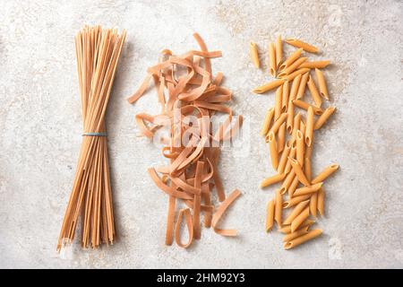 Wholegrain pasta assortment, spaghetti, tagliatelle and penne rigate, healthy noodles with fiber, protein, B vitamins and minerals, top view from abov Stock Photo