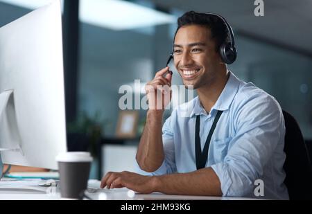 Have you heard about our latest package. Shot of a young man using a headset and computer in a modern office. Stock Photo