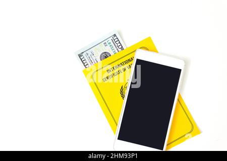Buying a fake Yellow international certificate of vaccination and with empty mock up screen smart phone for his image Stock Photo