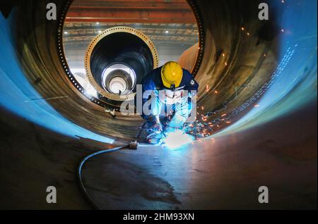 LIANYUNGANG, CHINA - FEBRUARY 8, 2022 - A worker produces a wind tower at a workshop of Chongshan Wind Equipment Company in Lianyungang Economic and T Stock Photo