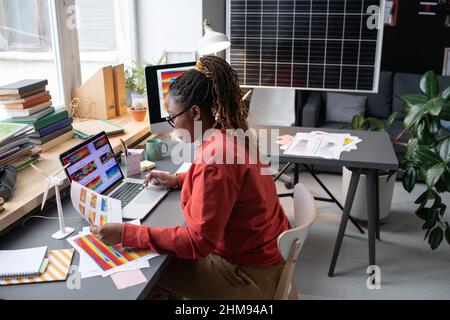 African businesswoman sitting at the table with laptop and working with documents, she examining charts and graphs Stock Photo