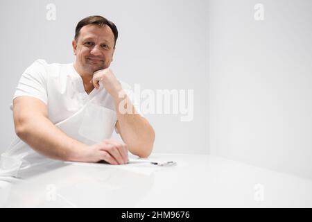 Middle aged male doctor sitting at the table Stock Photo