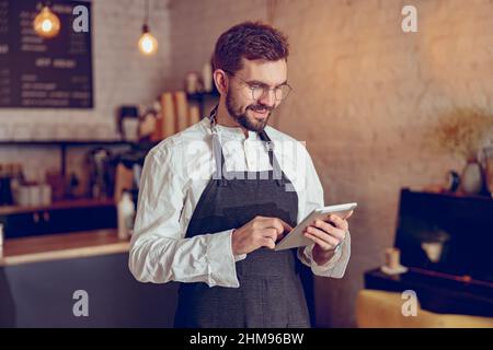 Cheerful male barista using tablet computer in cafe Stock Photo