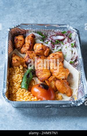 Take Away Turkish Chicken Kebab in Aluminum Foil Food Container. Take Out Dish. Ready to Eat and Serve. Stock Photo