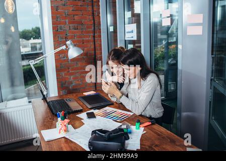 Two creative female designers choosing colors working with colour palette in the office. Stock Photo