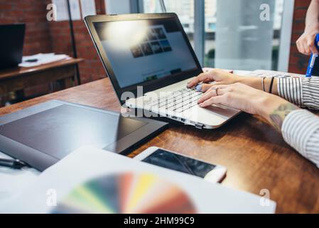 Close-up view of interior designer workspace with laptop, graphic tablet, phone and color palette on desk. Stock Photo