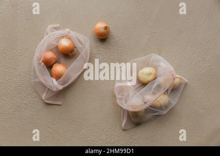Top view of eco bag with drawstring with onions and potatoes. Purchase without harm to nature in anti-plastic bags. Eco packs. Zero Waste. Stock Photo
