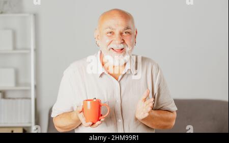 Elderly managing director with cup of tea. Mature caucasian man at home. Portrait of happy smiling senior businessman in modern office. Successful Stock Photo