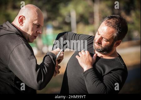 Knife threat. Kapap instructor demonstrates martial arts self defense disarming technique against knife attack. Weapon disarm training. Demonstration Stock Photo