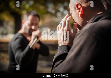 Knife threat. Kapap instructor demonstrates martial arts self defense disarming technique against knife attack. Weapon disarm training. Demonstration Stock Photo