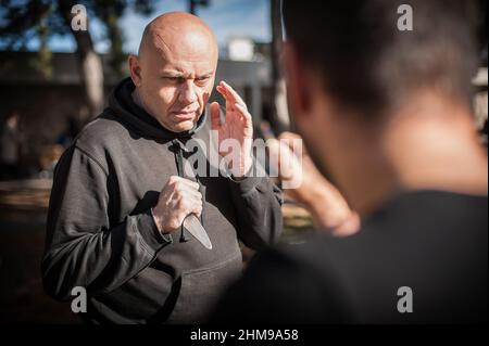 Knife threat. Kapap instructor demonstrates martial arts self defense disarming technique against knife attack. Weapon disarm training. Demonstration Stock Photo