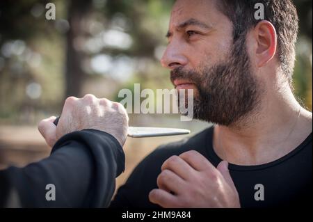 Knife threat. Kapap instructor demonstrates martial arts self defense disarming technique against knife attack. Weapon disarm training. Demonstration Stock Photo