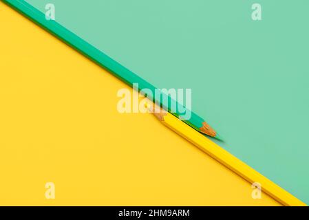 Yellow and green pencil placed on yellow and green paper background with copy space for your image or text Stock Photo