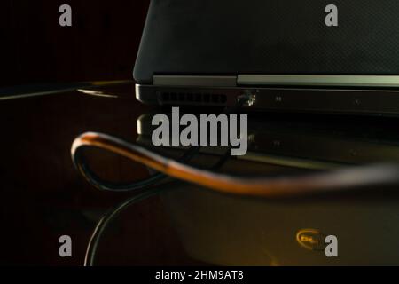 Ethernet cable plugged into a laptop in a dark room Stock Photo