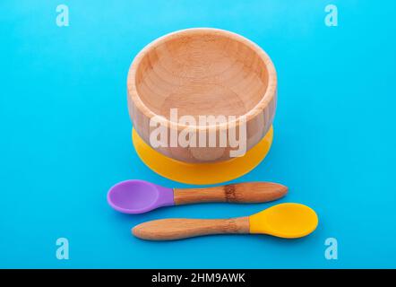 Wooden bowl. Bamboo plate with spoon isolated on blue background Stock Photo