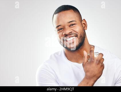 Grooming plays a major role in maintaining a high self-esteem. Studio portrait of a handsome young man spraying perfume on himself against a white Stock Photo