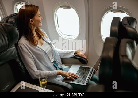 Female traveler using laptop in passenger plane Stock Photo