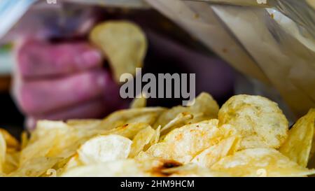 Hand is picking potato chip from bag Stock Photo