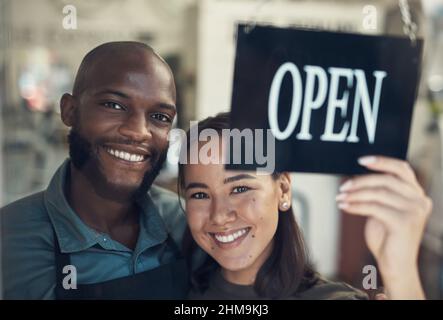 Were finally open. Shot of a young couple standing together and turning the sign on the door to their bicycle shop. Stock Photo