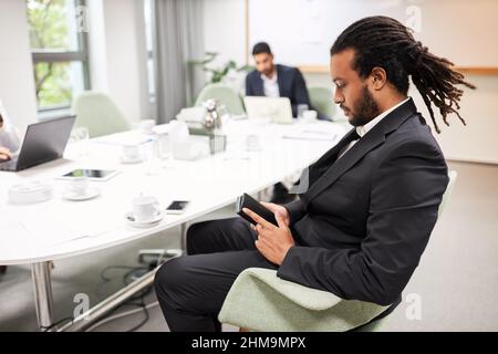 Young African business man sitting thoughtfully at the conference table during a break in the meeting Stock Photo