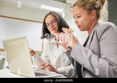 Two women in the creative IT team are working on the laptop PC developing a new website Stock Photo
