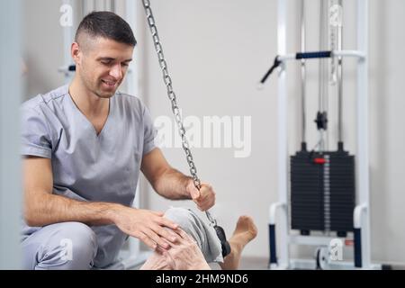 Male manual therapist helping old person with exercise Stock Photo