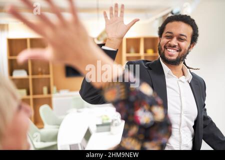 Two happy businessmen doing high five with hands in greeting in office Stock Photo